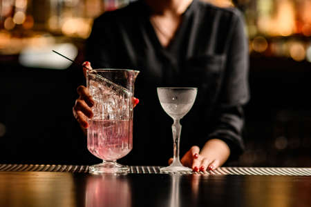 close-up view of crystal glass and mixing cup with drink on bar counterの写真素材