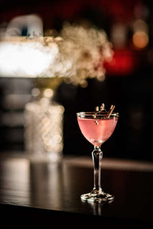 beautiful glass with cocktail decorated with blooming twig stands on the bar.の写真素材
