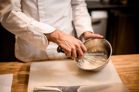Close-up of male chefs hands mixing ingredients in steel bowl