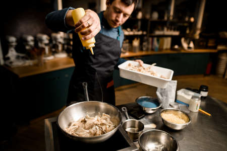high angle view of chef who pours sauce on mushrooms in fried panの写真素材