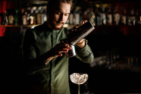 steel shaker cups in the hands of male bartender standing behind the bar counterの写真素材