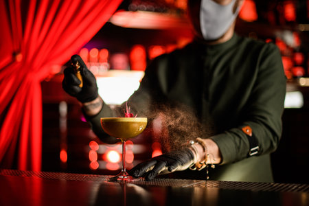 view of glass with cocktail decorated with flower on which man bartender sprinklesの写真素材