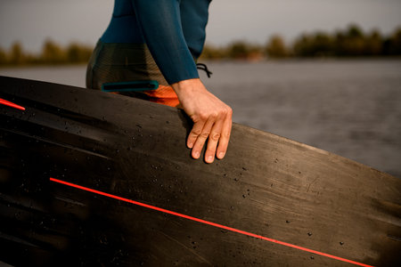 Close-up of mans hand holding black wakeboarding board.の写真素材
