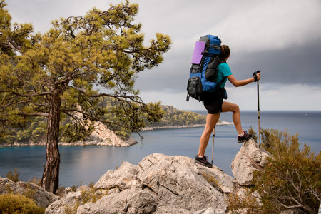 Woman with backpack and trekking sticks travel on lycian way in Turkey