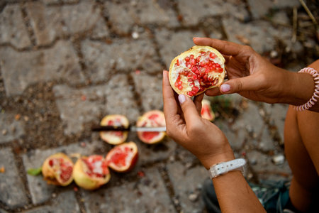 Top view of pomegranate fruit with red ripe seeds in womans hands