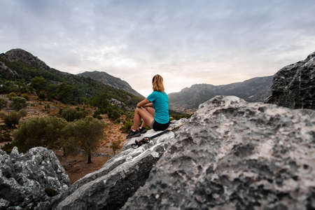 back view on woman resting on stone and enjoying beautiful mountains landscape.の写真素材