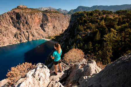 high angle view of woman standing on large stone and enjoying view of sea bayの写真素材