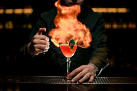 great view of beautiful glass with cocktail that the bartender sets fire toの写真素材
