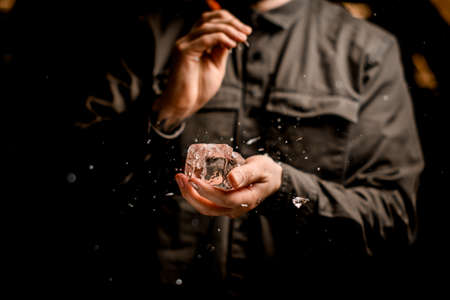 beautiful view of big ice cube in the hand of man bartenderの写真素材