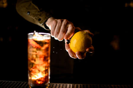close-up of male hands with lemon that carefully peels off zest from it with knifeの写真素材