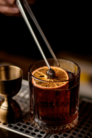beautiful close-up view on glass with cocktail decorated with orange slice and small pine coneの写真素材