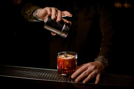 beautiful view of cocktail glass on bar which man bartender decorates with powdered sugarの写真素材