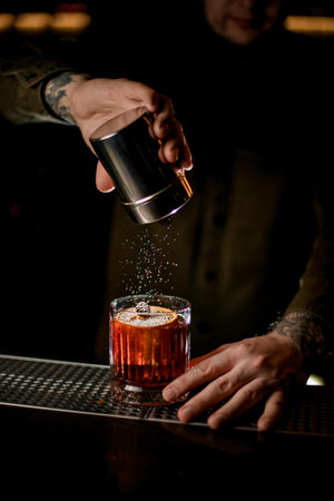 beautiful view of cocktail glass on bar which bartender decorates with powdered sugar
