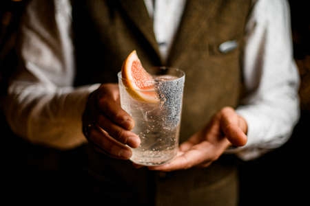 view of transparent glass with freshness drink in hands of male bartenderの写真素材