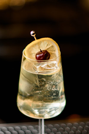 close-up of glass with refreshing cold drink garnished with lemon slice and berry