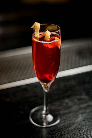 Close-up view on wine glass with red beverage decorated with zest on barの写真素材