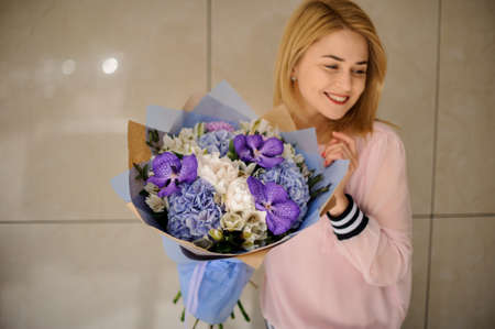 Great floral bouquet of different fresh flowers in hands of smiling blonde womanの写真素材