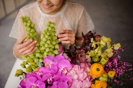 close-up of different fresh flowers in large bouquet and smiling woman florist nearbyの写真素材