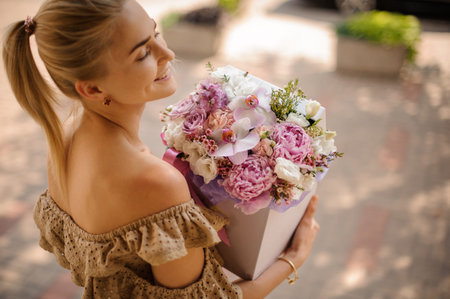 woman holding box with beautiful composition of different natural flowers in her handsの写真素材
