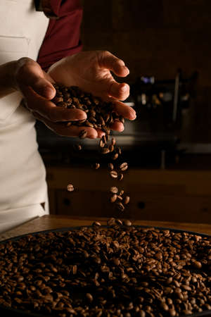 excellent view of female hands with roasted coffee beans pouring out of cupped handsの写真素材
