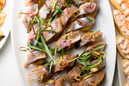 top view of pieces herring served with onions and decorated by rosemary