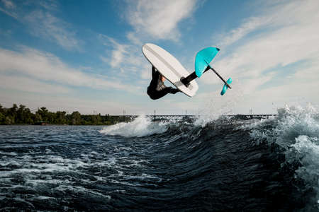 marvelous view of foilboard on which man effectively performs trick over the waveの写真素材