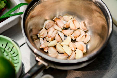 white fresh raw cloves of garlic in bowl stainless steel on tableの写真素材