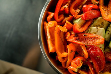 part of bowl with chopped red bell pepper and zucchini sprinkled with seasoning.の写真素材