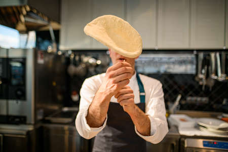 selective focus on the dough that the chef throws up the airの写真素材