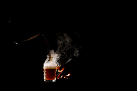 Wonderful view of illuminated transparent steaming cup at dark in which pouring drinkの写真素材