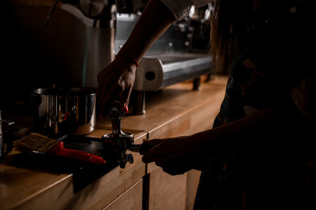 Female barista hands holding portafilter and coffee tamper making an espresso coffee.の写真素材