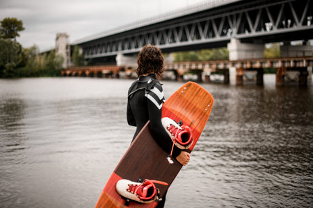 back view of wet woman standing with board for wakeboarding in her handの写真素材