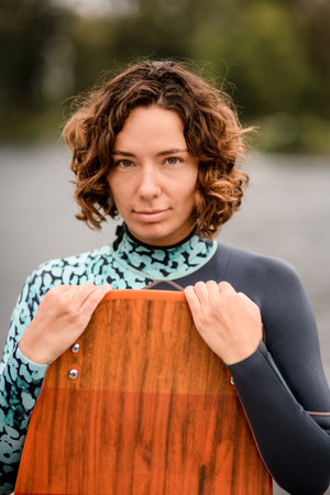 portrait of attractive woman who is holding wakeboarding board by her hands.の写真素材