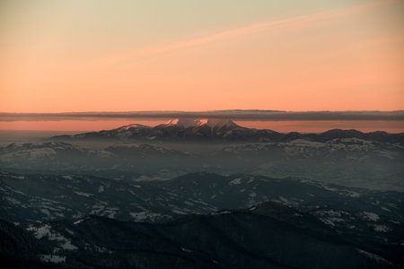 magnificent view of mountain peak against background of bright orange sky with clouds on top
