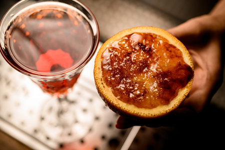 Close-up of piece of orange in womans hand with caramel crust on it