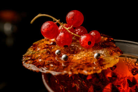 beautiful view of burnt caramel crust with red currant on glass of drinkの写真素材