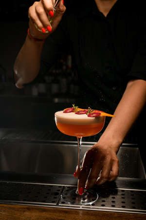 magnificent view of glass with frothy drink decorated with flowers on which bartender sprinklesの写真素材