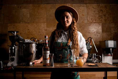 UKRAINE, KYIV - MAY 19, 2021: woman stands at table with glass, bottle of syrup and jug of orange juiceのeditorial素材