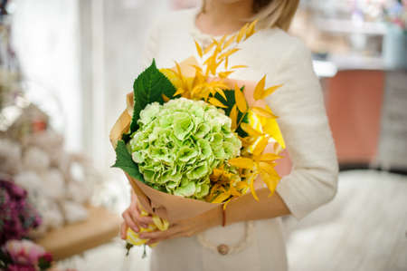 beautiful bouquet of hydrangea and bright yellow branches in the hands of womanの写真素材
