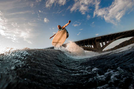 great view of male wakeboarder while jumping over splashing waveの写真素材