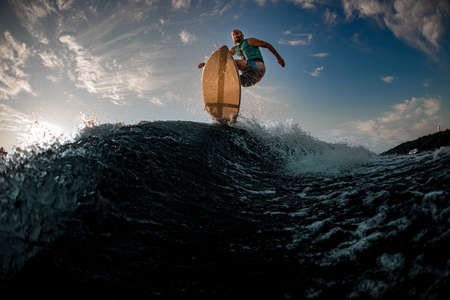 magnificent bottom view of male wakeboarder while jumping over splashing waveの写真素材