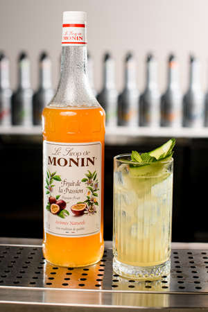 UKRAINE, KYIV - MARCH 11, 2021: Beautiful view of bottle of Monin passionfruit syrup and glass with cocktail on tableのeditorial素材