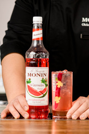 UKRAINE, KYIV - MARCH 11, 2021: bottle of Monin watermelon syrup and glass with tasty cold cocktail on tableのeditorial素材