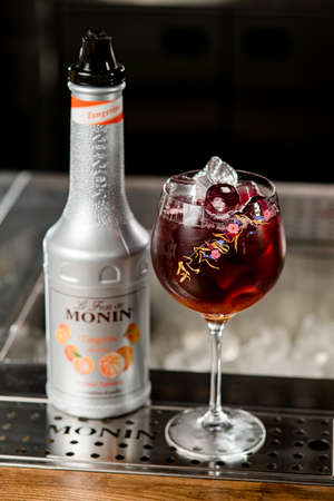 UKRAINE, KYIV - MARCH 11, 2021: high angle view of bottle of tangerine syrup by Monin and beautiful glass of cold cocktailのeditorial素材
