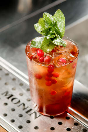 UKRAINE, KYIV - MARCH 12, 2021: Close-up view of glass of tasty cocktail with cranberries and mint leaf on bar counterのeditorial素材