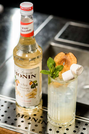 UKRAINE, KYIV - MARCH 12, 2021: Angle view of bottle of Monin white chocolate and glass of cold drink on bar counterのeditorial素材