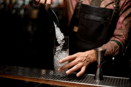 Clear tall glass in which poured crushed ice from scoopの写真素材