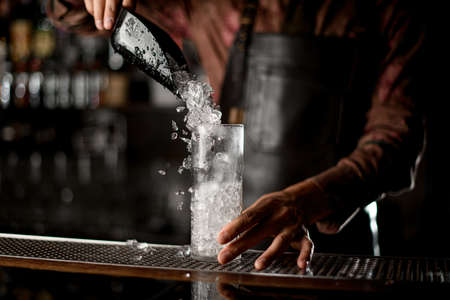transparent tall glass in which poured crushed ice from steel scoopの写真素材