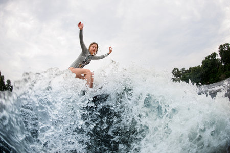 magnificent view on splashing wave and active woman on wakesurf rides down on itの写真素材