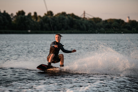 active man in wetsuit balancing on wakeboard and riding a splashing wave.の写真素材